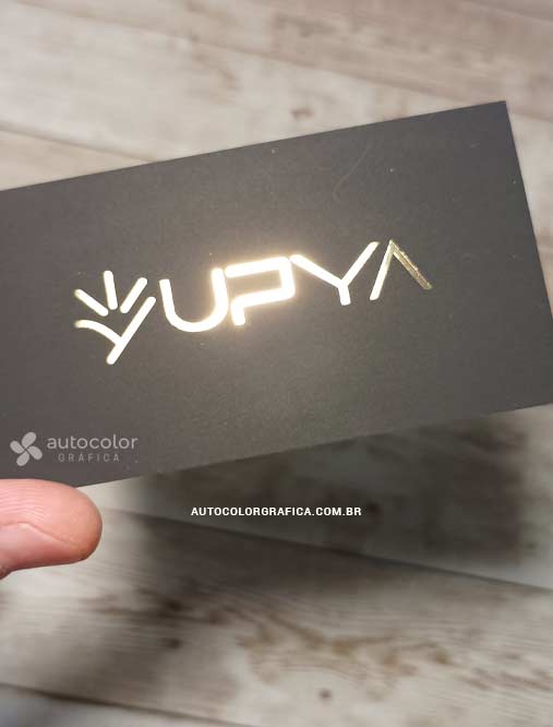 Cartão preto com logotipo em foil dourado refletindo a luz